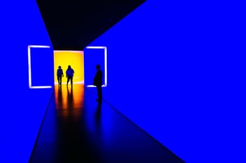 People standing near the light at the end of a dark hallway